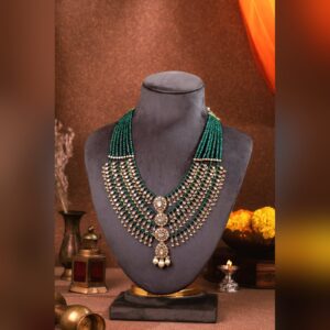 Layered polki bridal necklace with emerald beads on a display bust, by Sri Sai Krishna Jewellers
